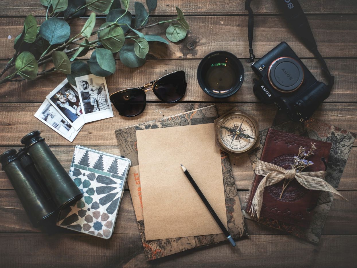 Travel notes, photographs and film gear on a wooden table