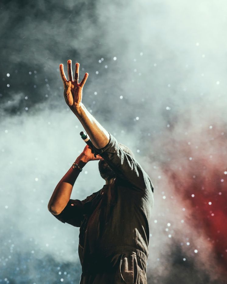 Performer silhouetted in stage haze, arm raised